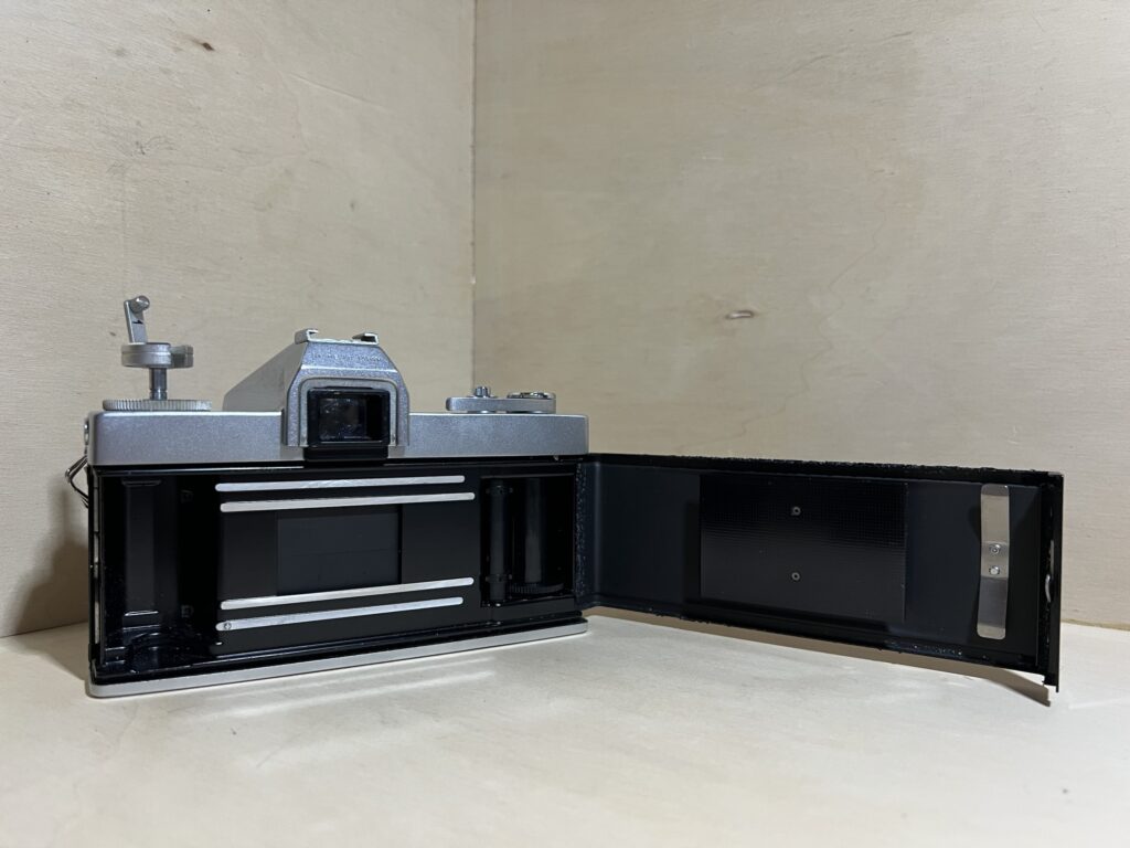 Dos d’un reflex argentique ouvert sur la table de l’atelier
